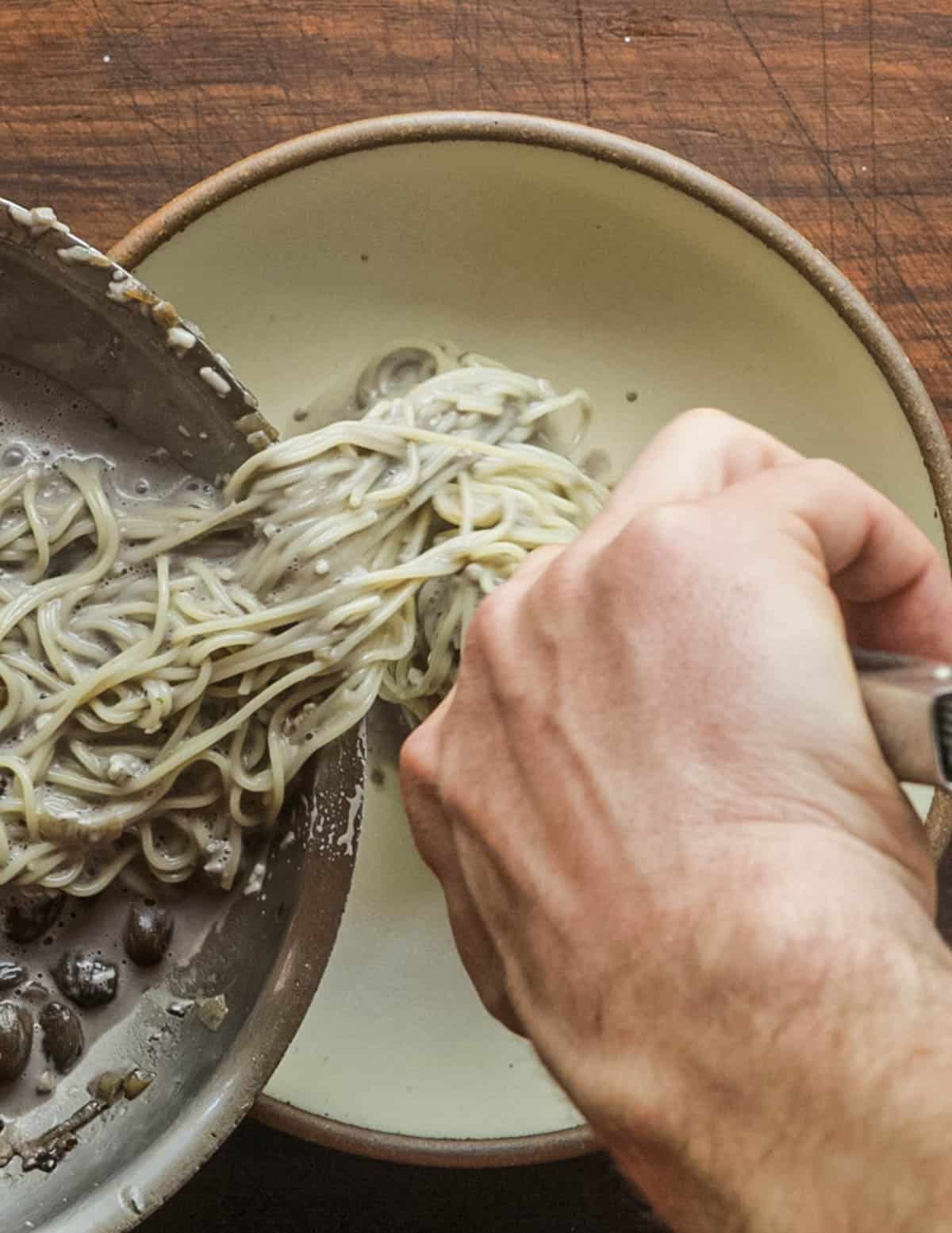 Twirling pasta noodles with mushroom sauce into a bowl. 