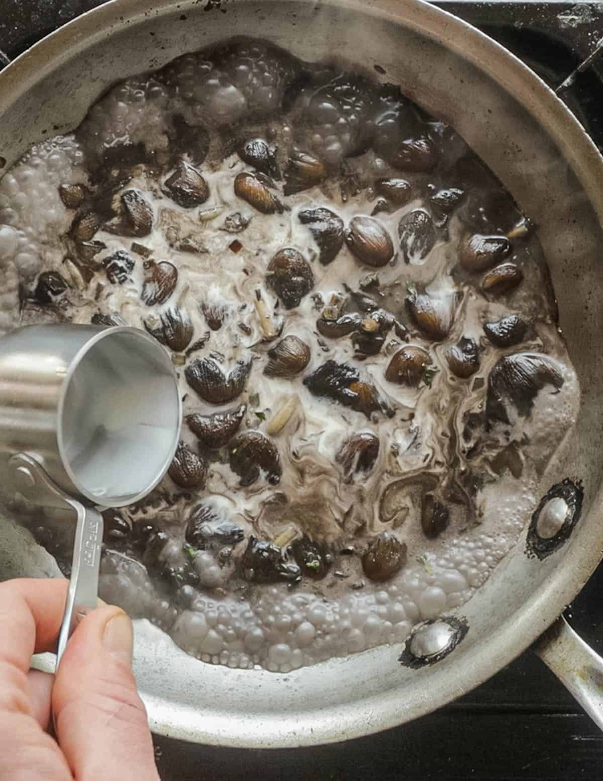 Adding heavy cream to a pan of mushroom sauce. 