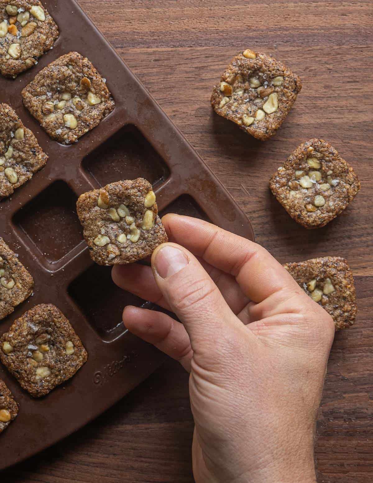 removing black walnut cookies from a silicone baking mold after cooking. 