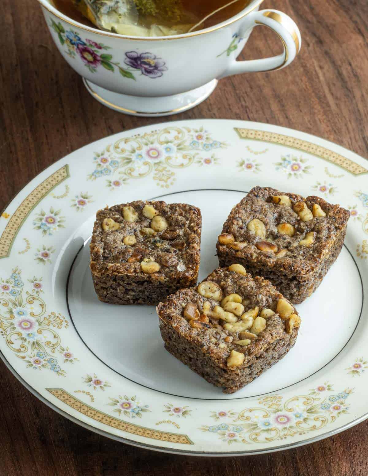 Black walnut cookies tinted by adding ground fruit powder to the dough on a plate next to a cup of tea. 