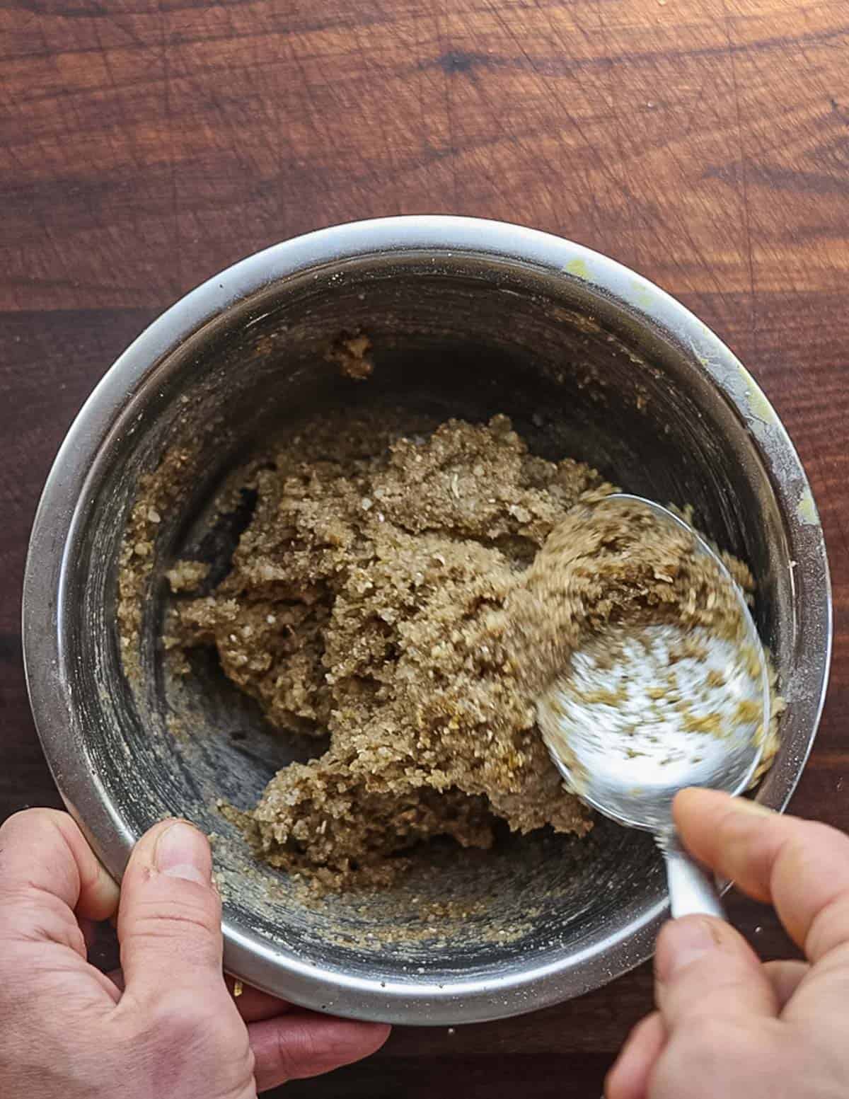 Mixing black walnut cookie dough in a bowl with a spoon. 