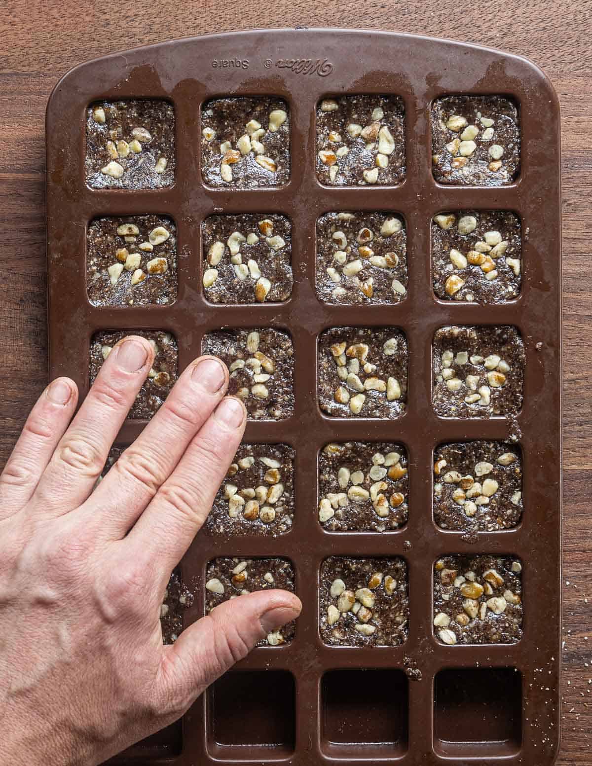 Pressing black walnuts into the top of cookies in a mold. 