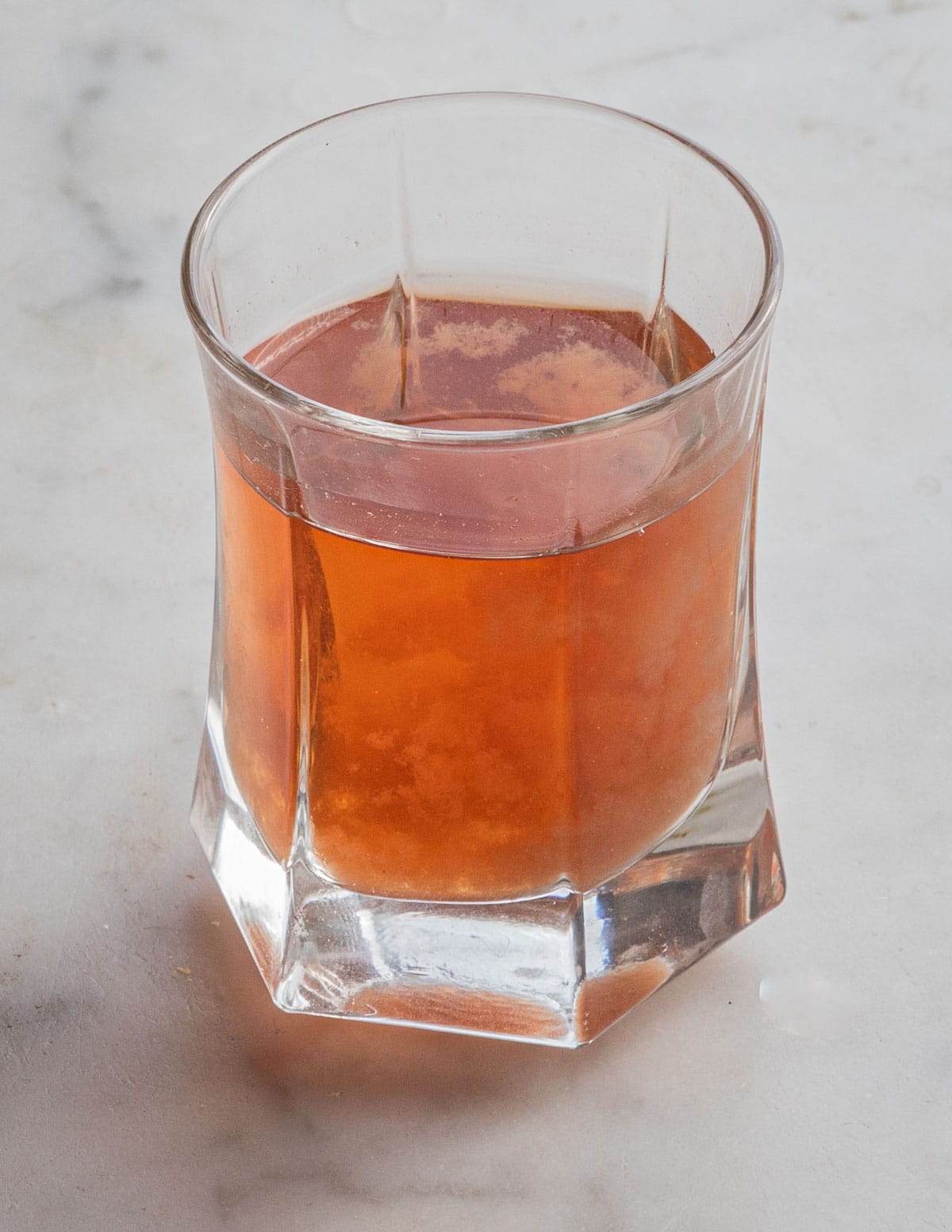 A cup of infused nettle tea showing a light orange color. 