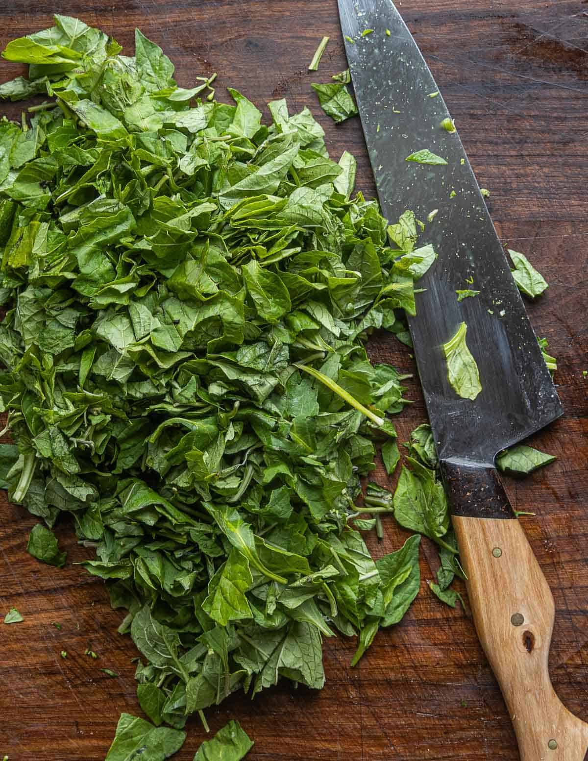 Slicing black nightshade greens or hierba mora with a chef knife for soup. 