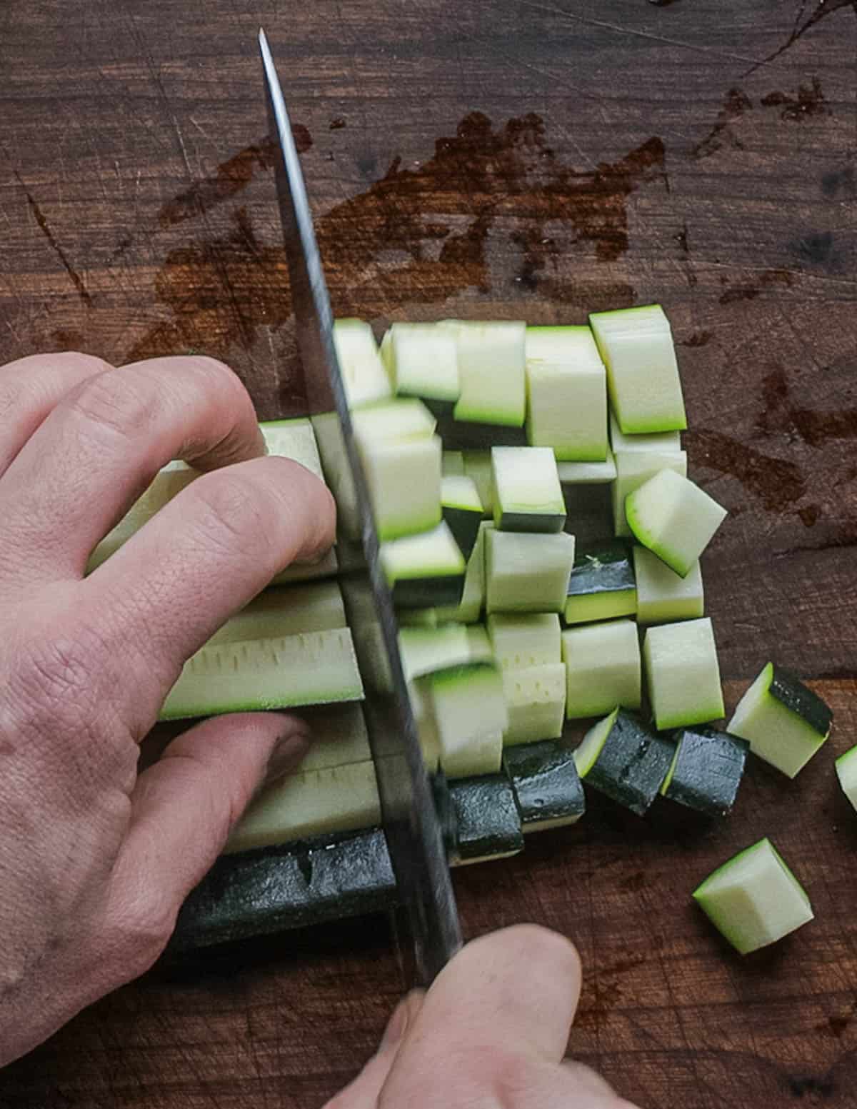 Dicing calabaza zucchini with a chef's knife. 