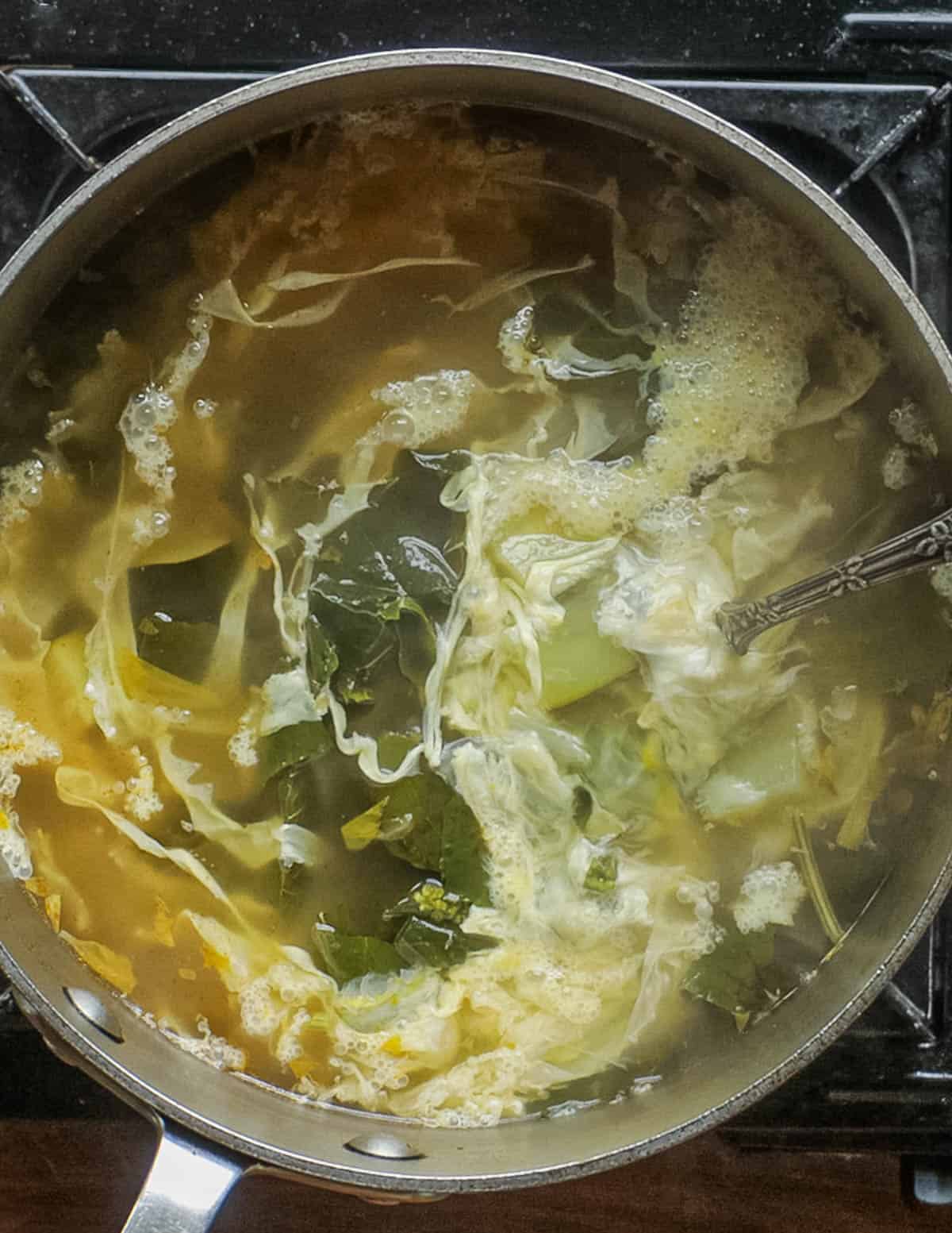 A pot of finished sopa de mora showing ribbons of cooked egg. 