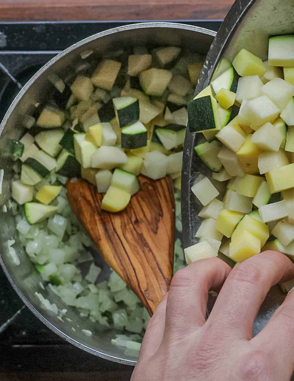 Adding diced zucchini and potato to the soup. 