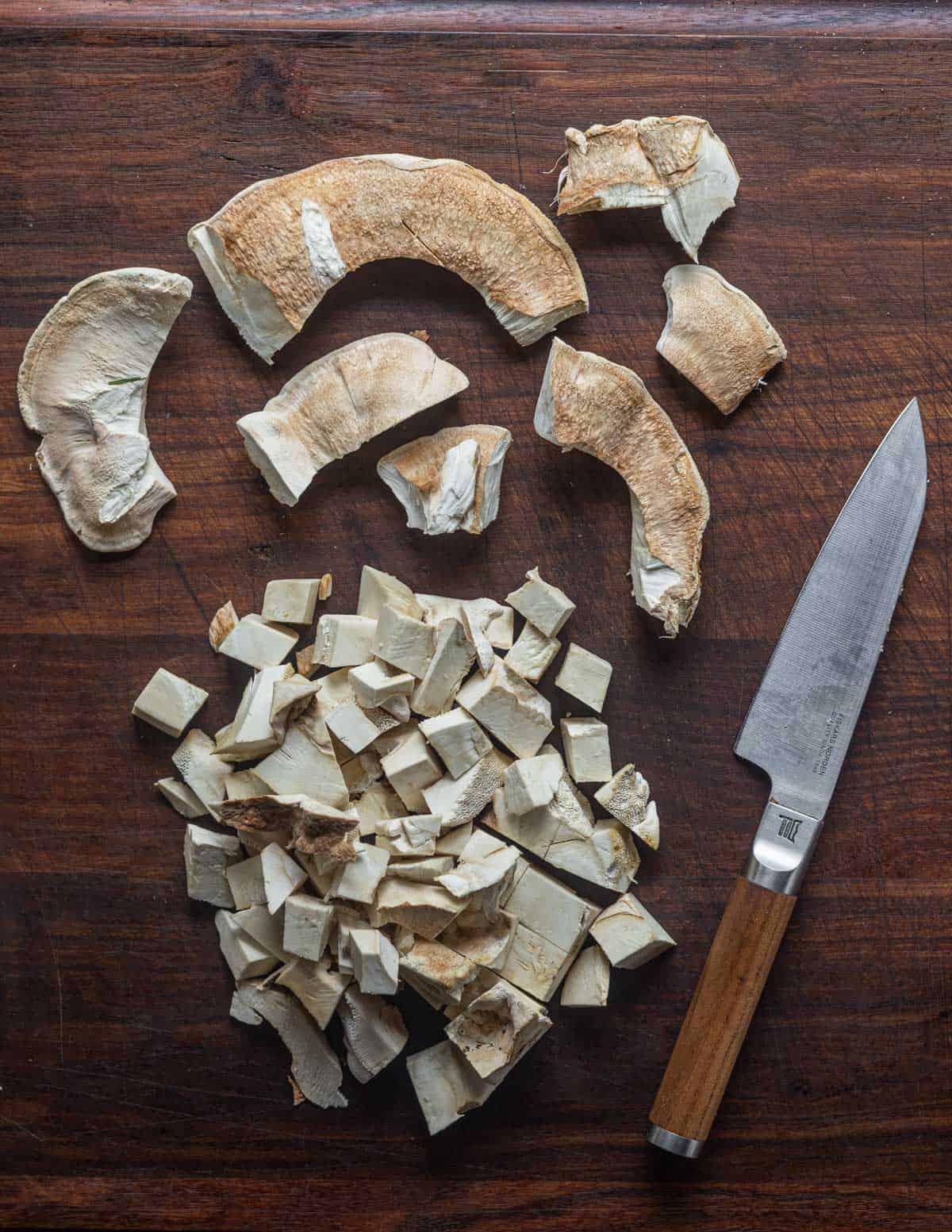 Cutting berkeley's polypore into pieces for cooking, showing the woody stem diced for stock and the outer margin removed for slicing. 