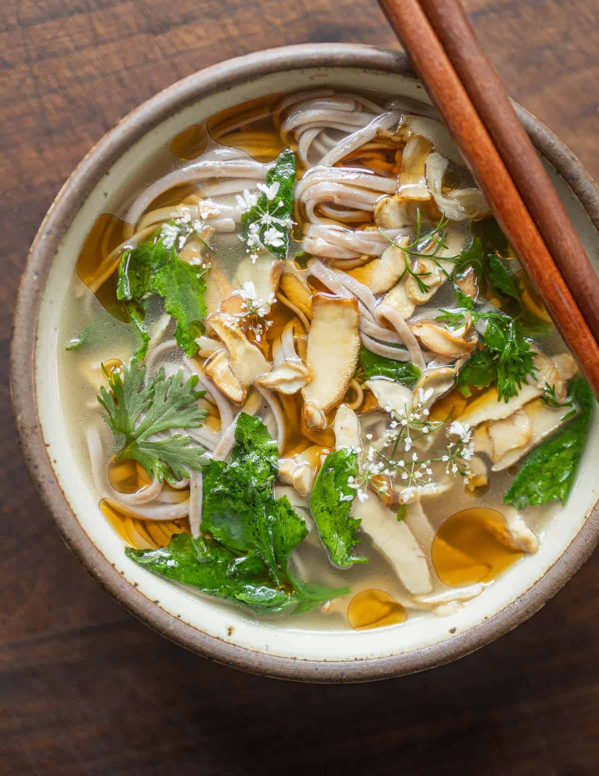 Berkeley's polypore soup in a small bowl seen from the top down garnished with cilantro flowers, soba noodles and lambsquarters. 