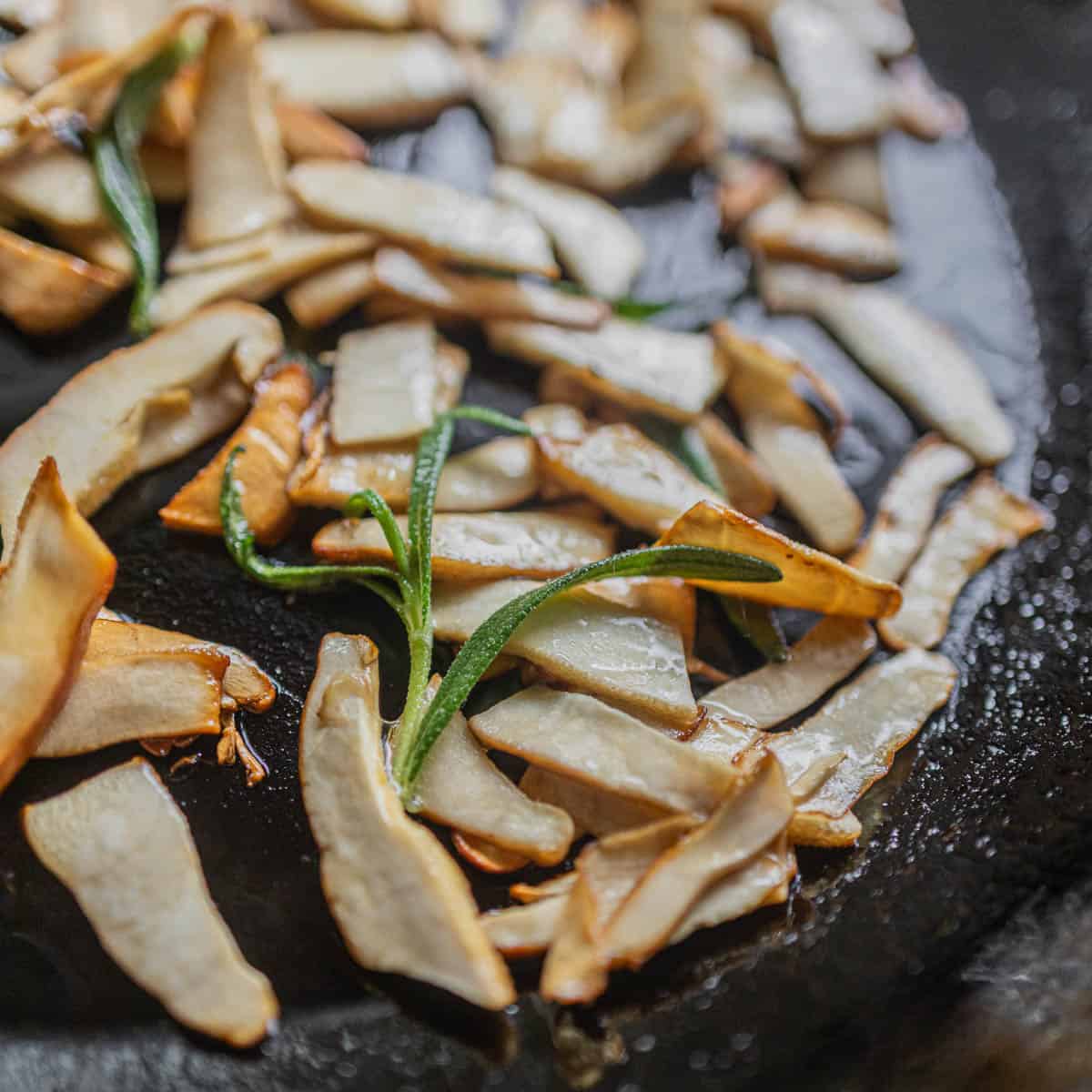 Cooking thinly sliced Berkeley's polypores in a pan with rosemary leaves. 