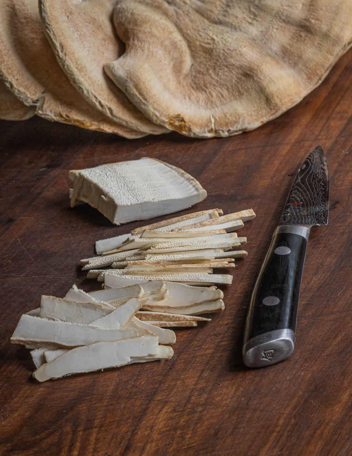 Thinly slicing the tender edges of a Berkeley's polypore mushroom. 