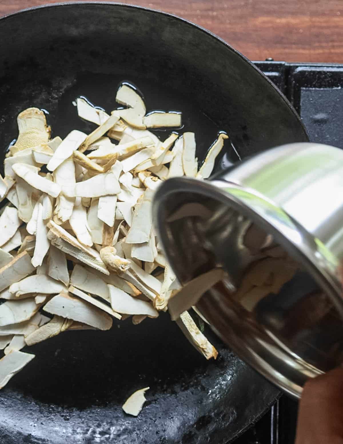 Adding thinly sliced berkeley polypore mushrooms to a pan of oil. 