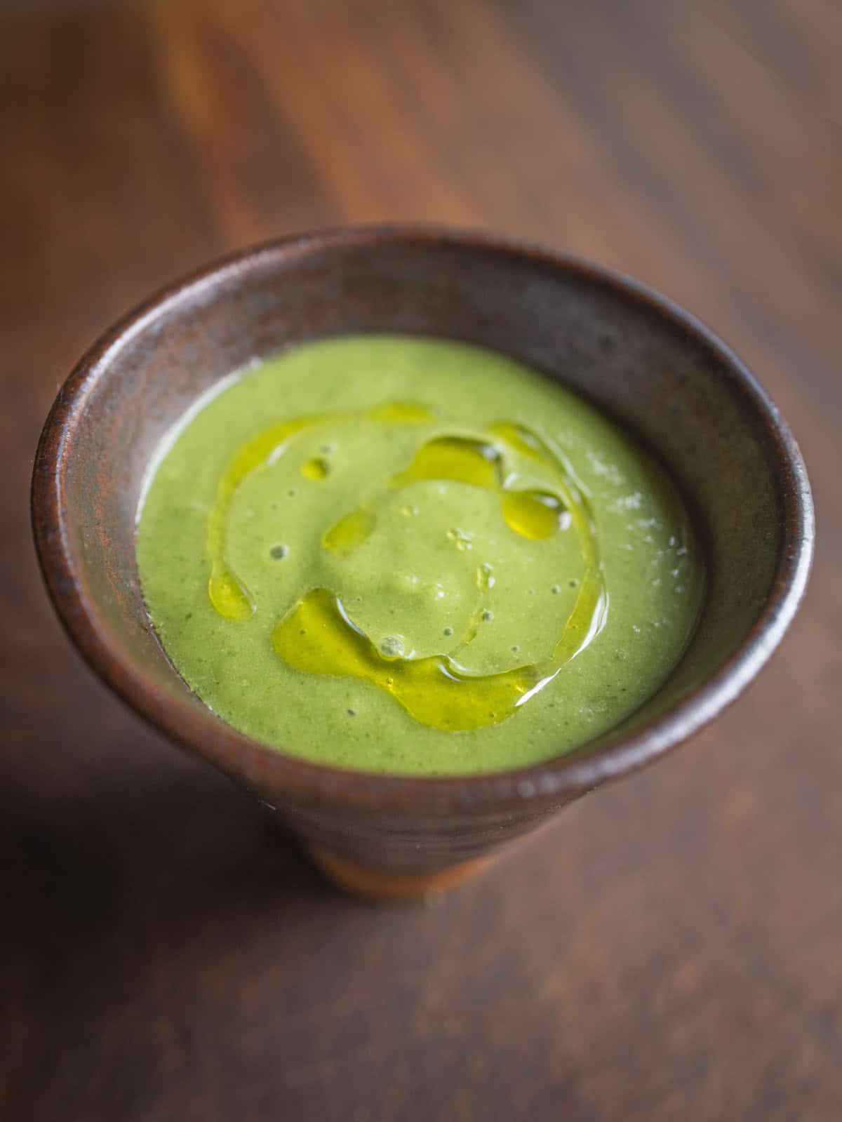 A small cup filled with a green smoothie of pureed pellitory leaves and cucumbers. 