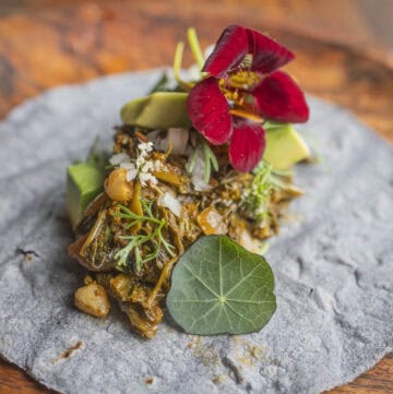 Plant based taco garnished with cilantro flowers, nasturtium flowers and leaves and avocado.