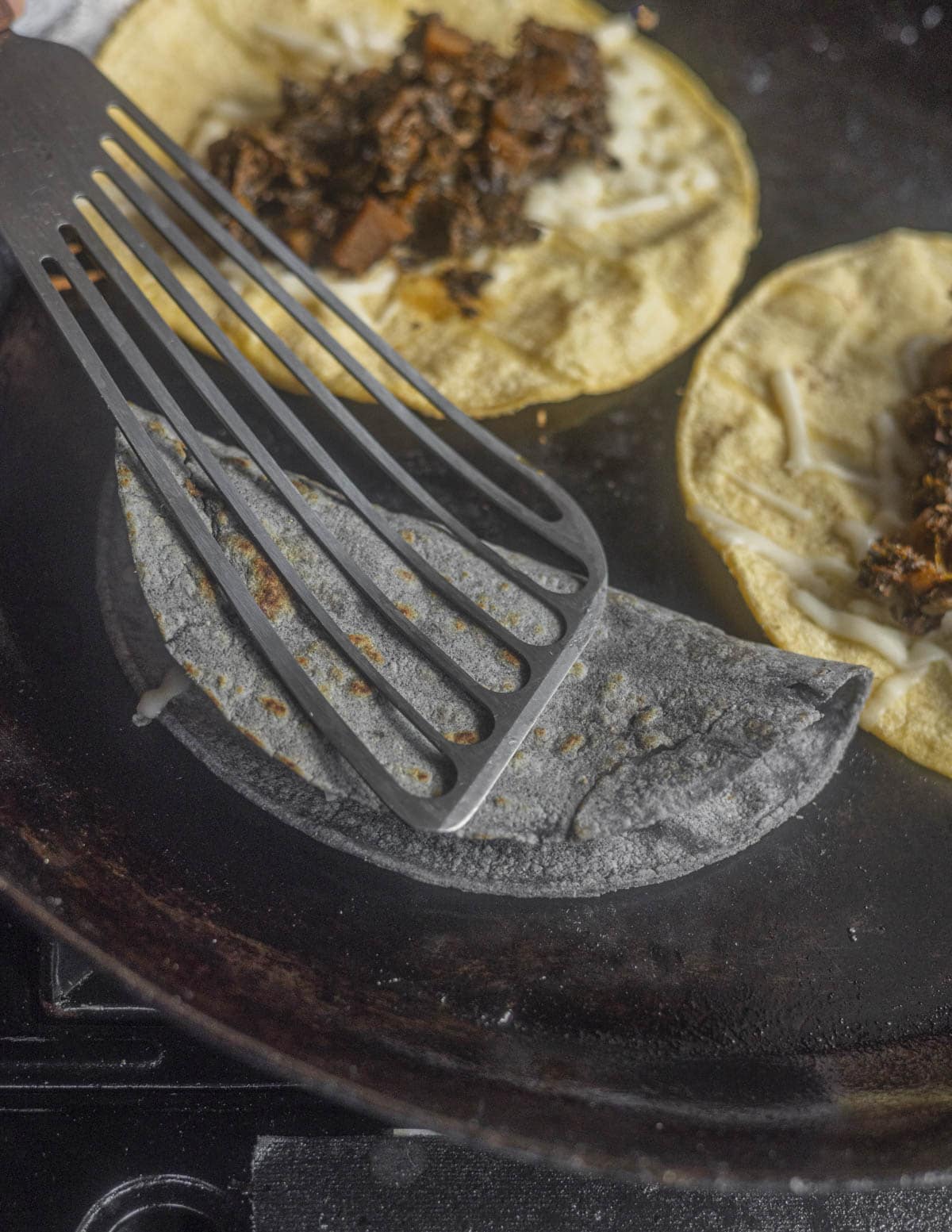 Folding over a plant based quesadilla with a spatula and frying it crisp. 