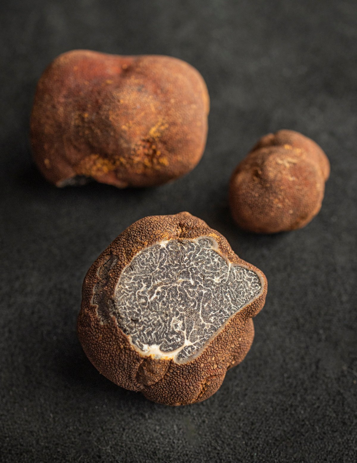 Three Appalachian truffles or Michigan truffles (Tuber canaliculatum) with one cut showing the inner brown