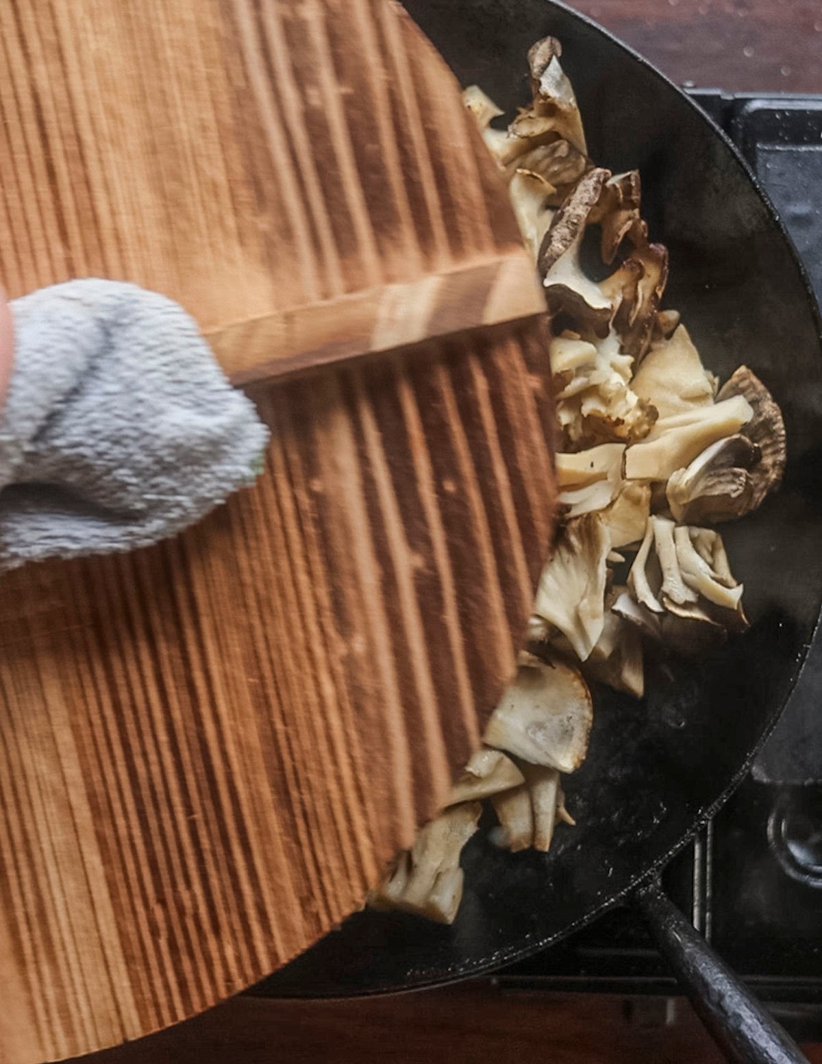 Covering a pan of mushrooms with a lid while they cook. 