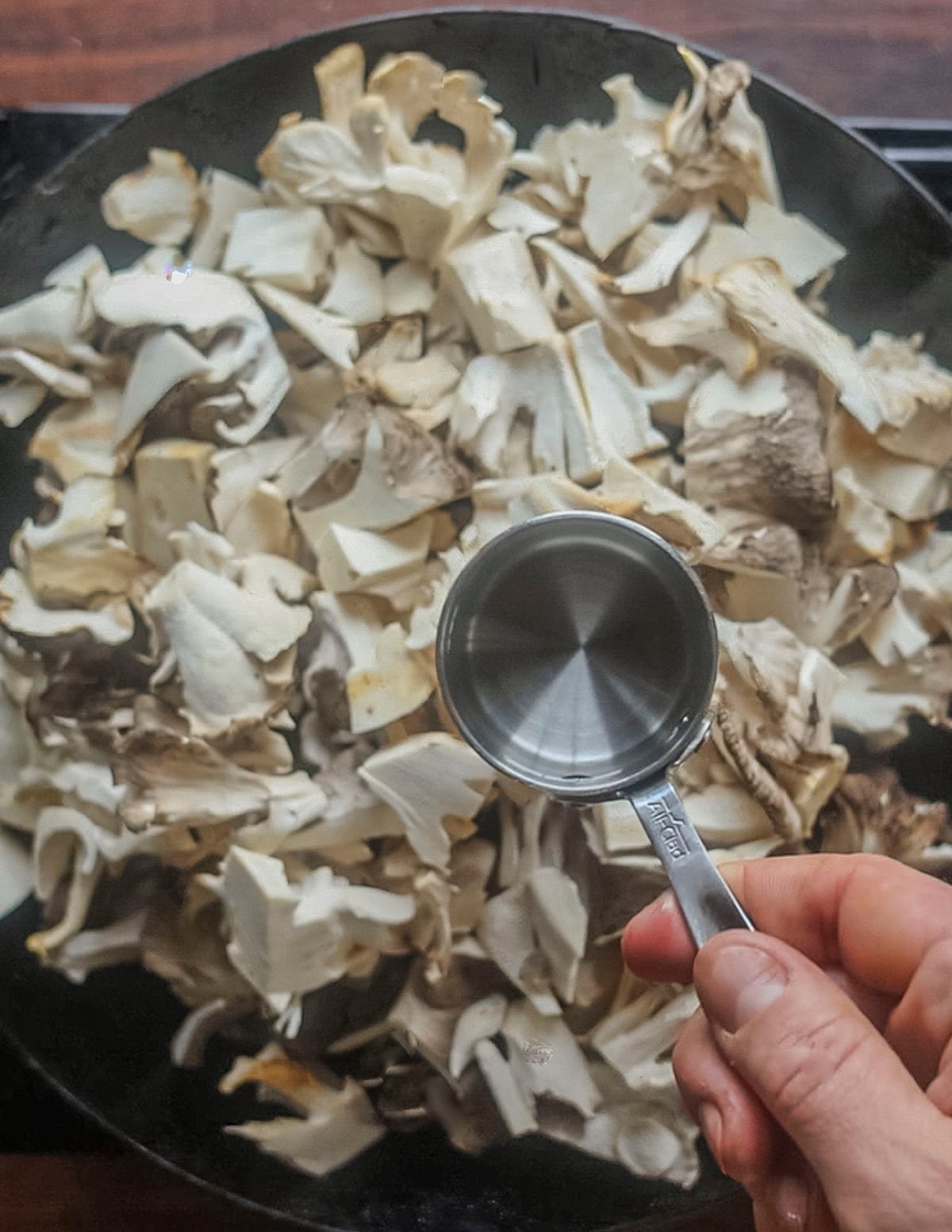 Adding water to a pan of mushrooms before cooking. 