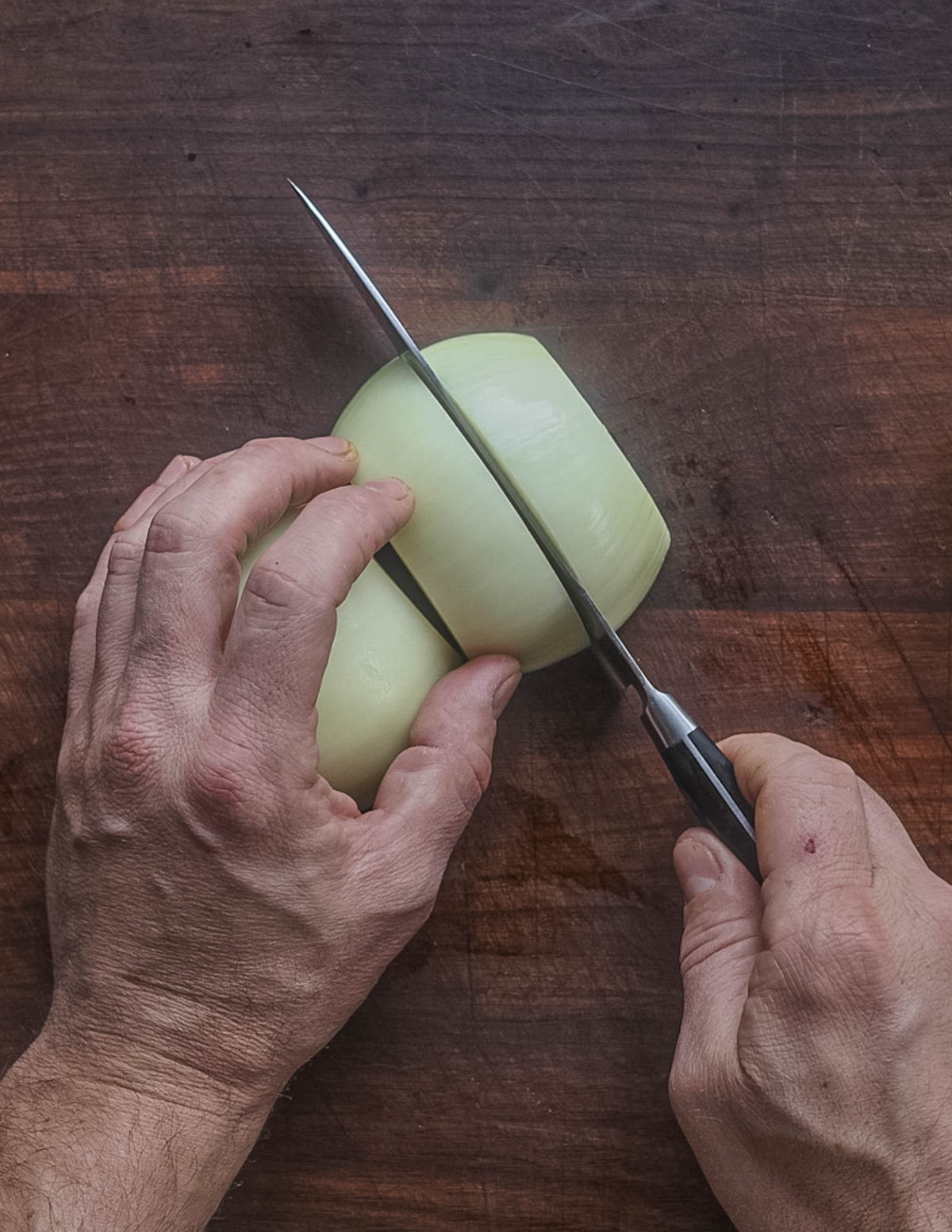 Slicing an onion in half to prepare it for making caramelized onions. 