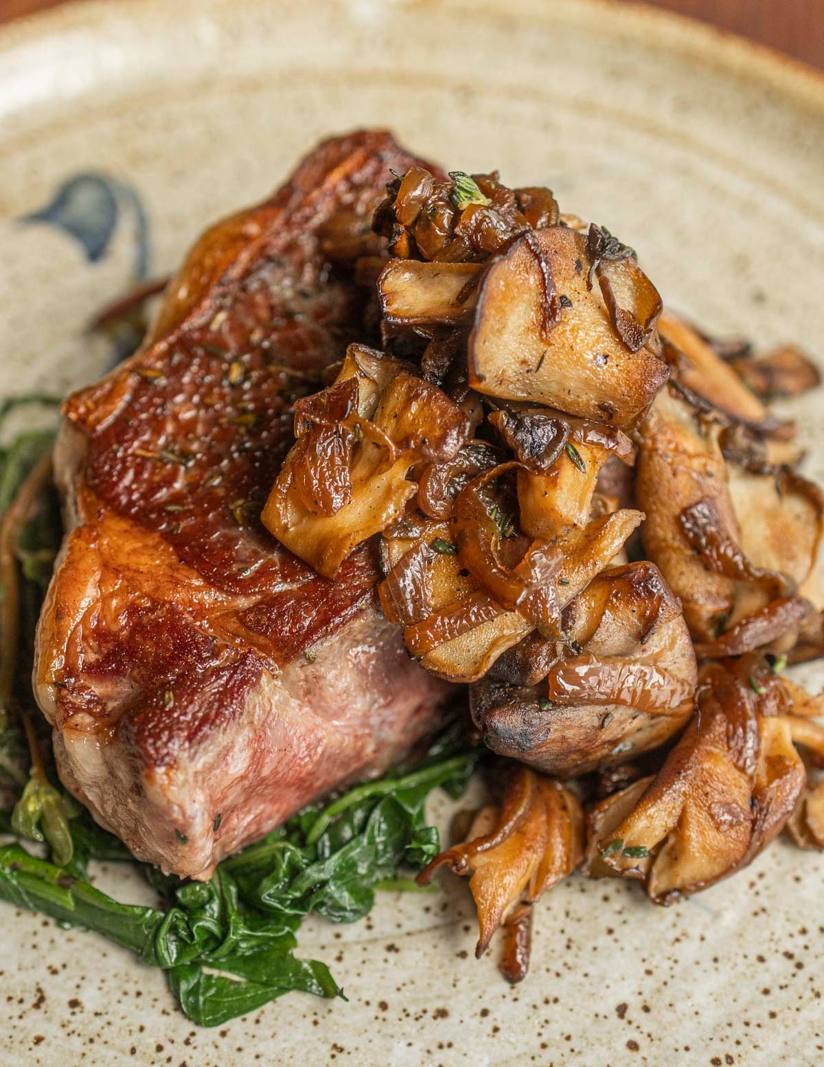 A new york strip steak garnished with caramelized onions and mushrooms. 