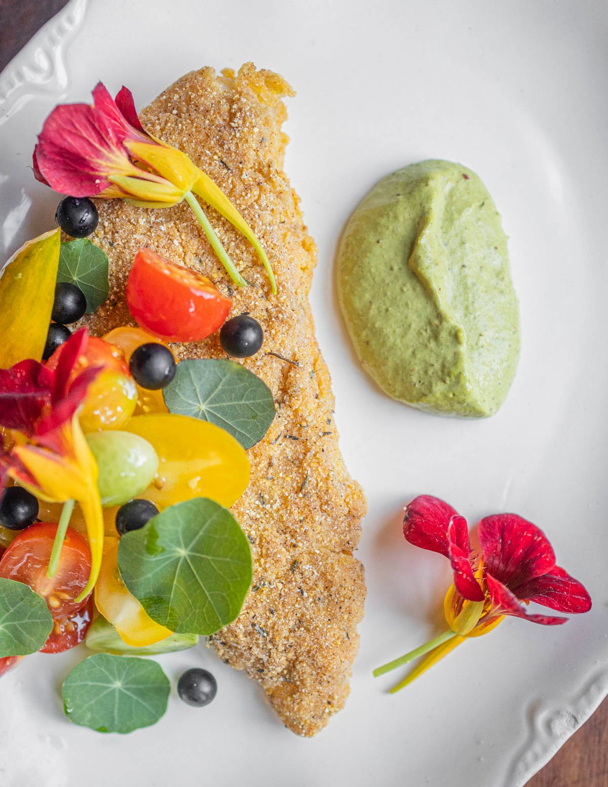 Fried walleye with nasturtium leaves and flowers, lovage sauce and edible black nightshade berries. 