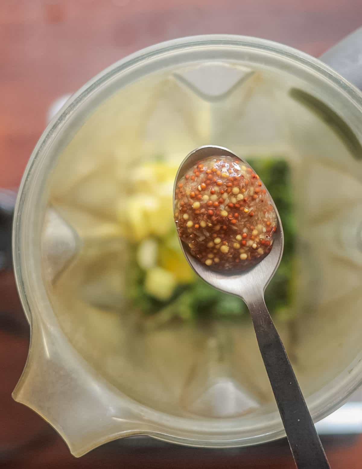 Adding a spoonful of mustard to a blender to make aioli. 