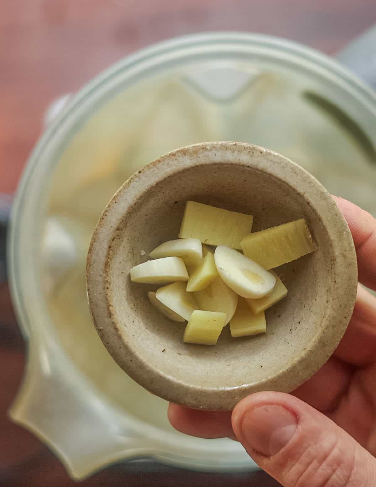 Adding chopped garlic to a blender. 