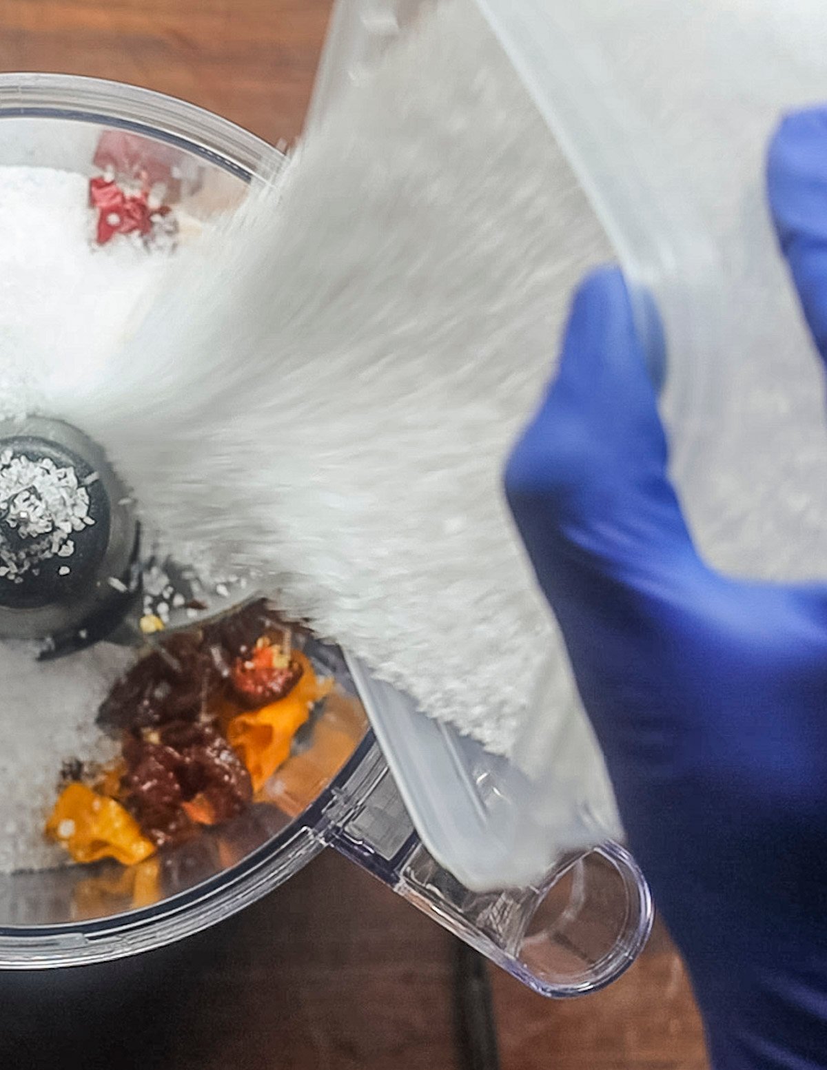 Adding salt to a food processor filled with super hot peppers. 