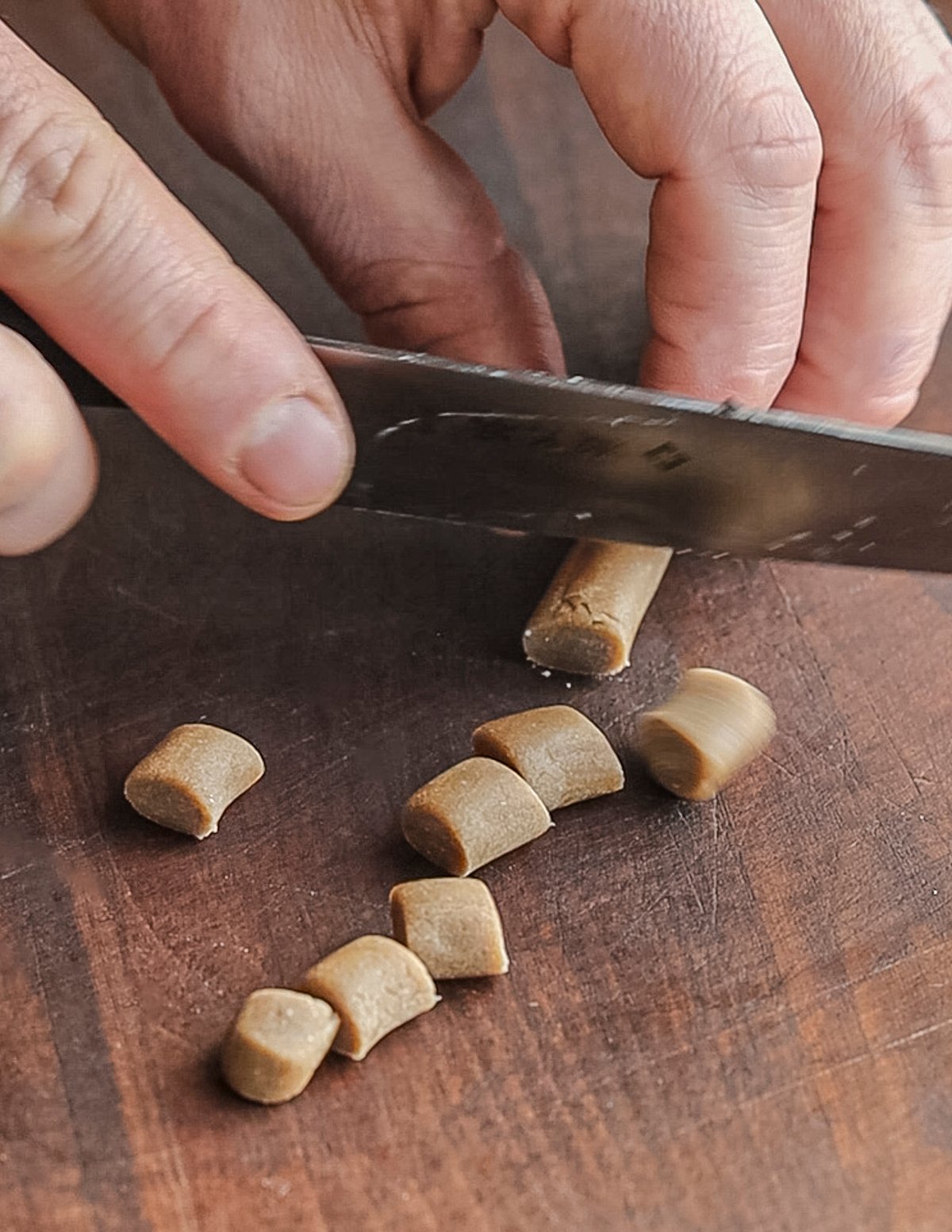 Cutting a rope of chestnut gnocchi dough into pieces. 