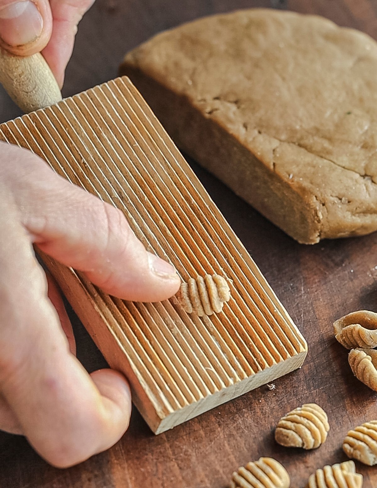 Rolling chestnut gnocchi off of a gnocchi board. 