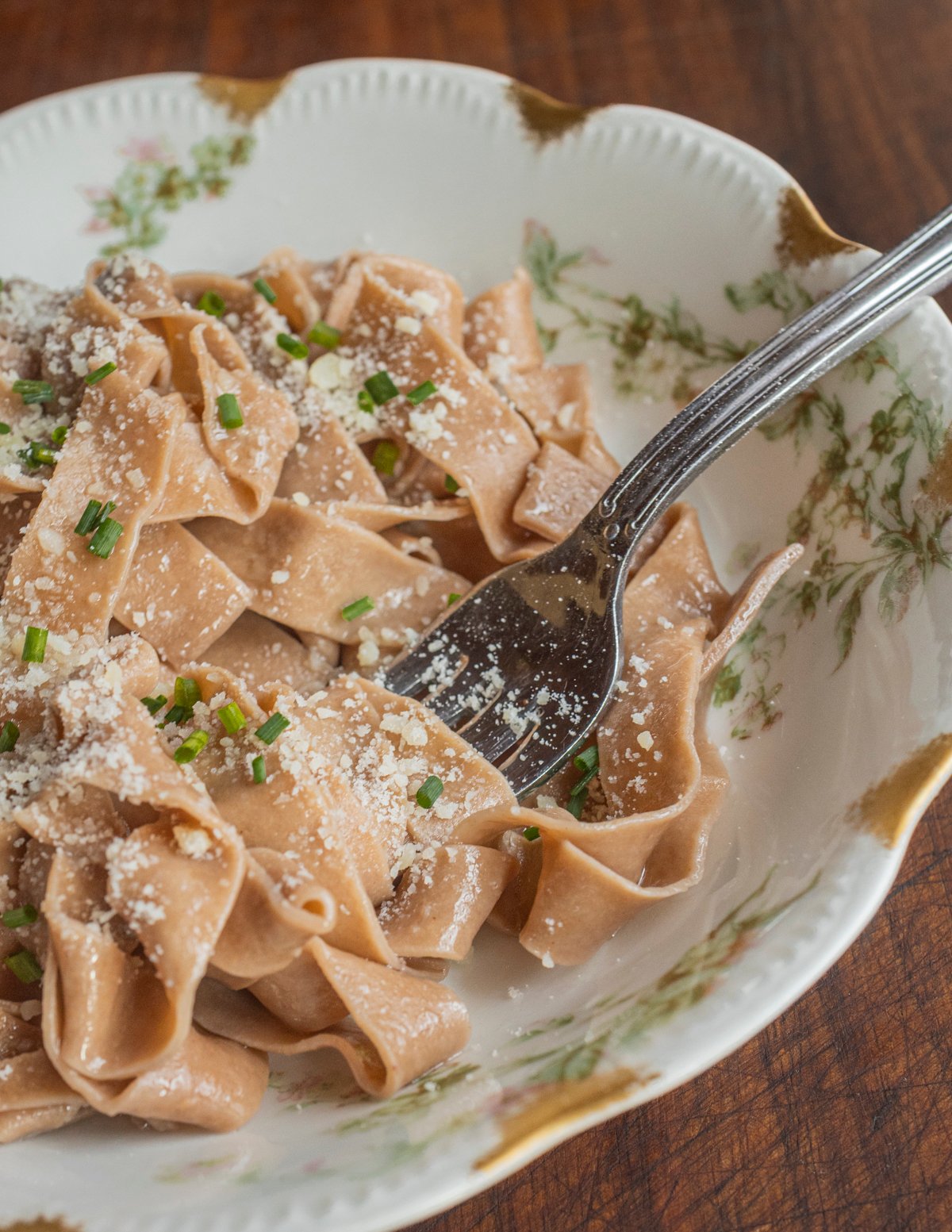 A finished bowl of chestnut flour pasta served with brown butter, chives and parmesan cheese.