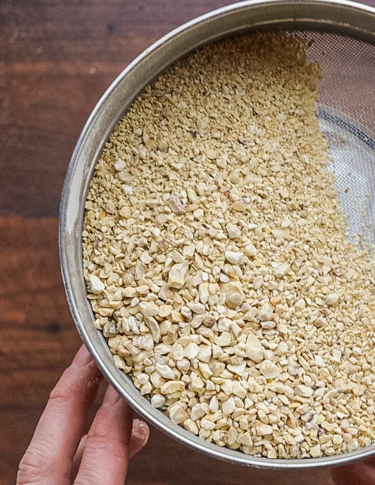 Sifting chestnut flour through a sieve to remove large particles. 