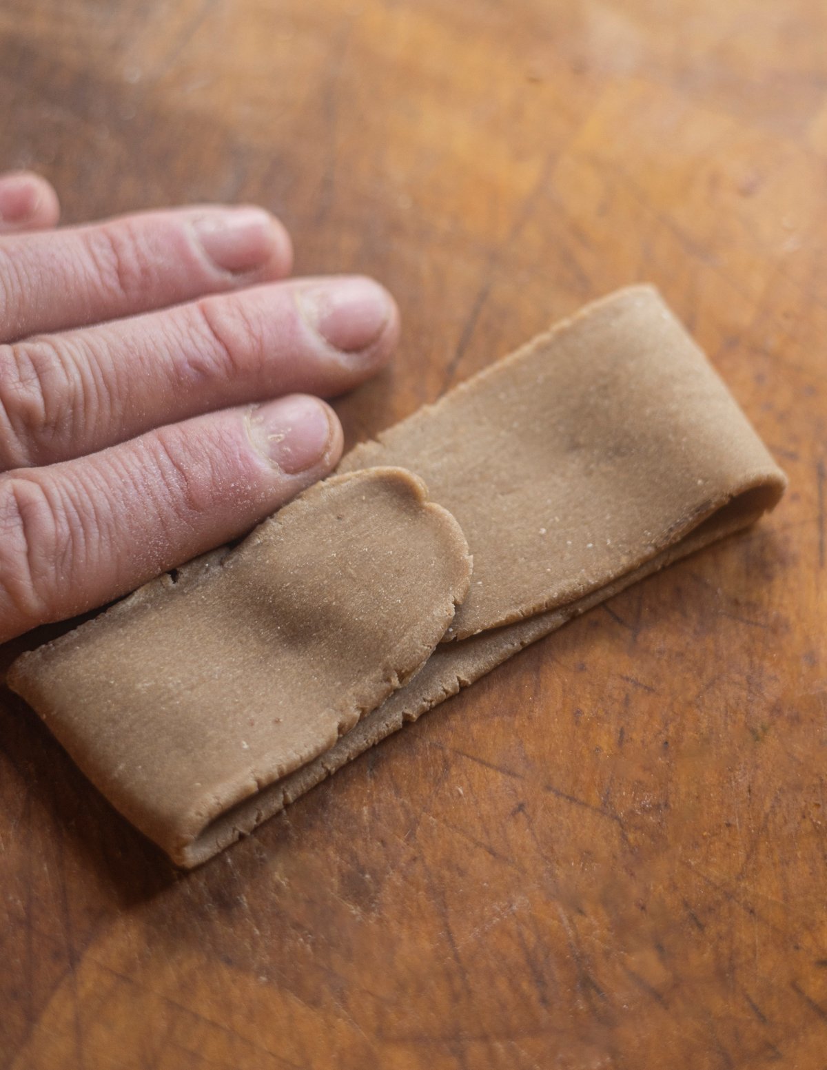 Folding pasta dough over itself in thirds. 