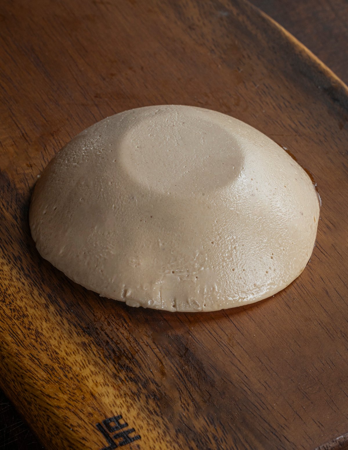 Cooked, chilled chestnut polenta that's been unmolded onto a cutting board and is ready to slice.