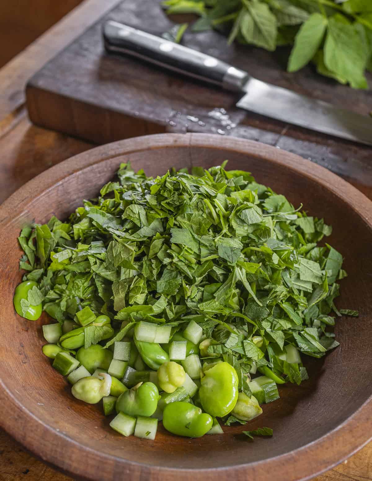 Mixing sliced ground elder leaves with fava beans, green chickpeas and cucumbers. 
