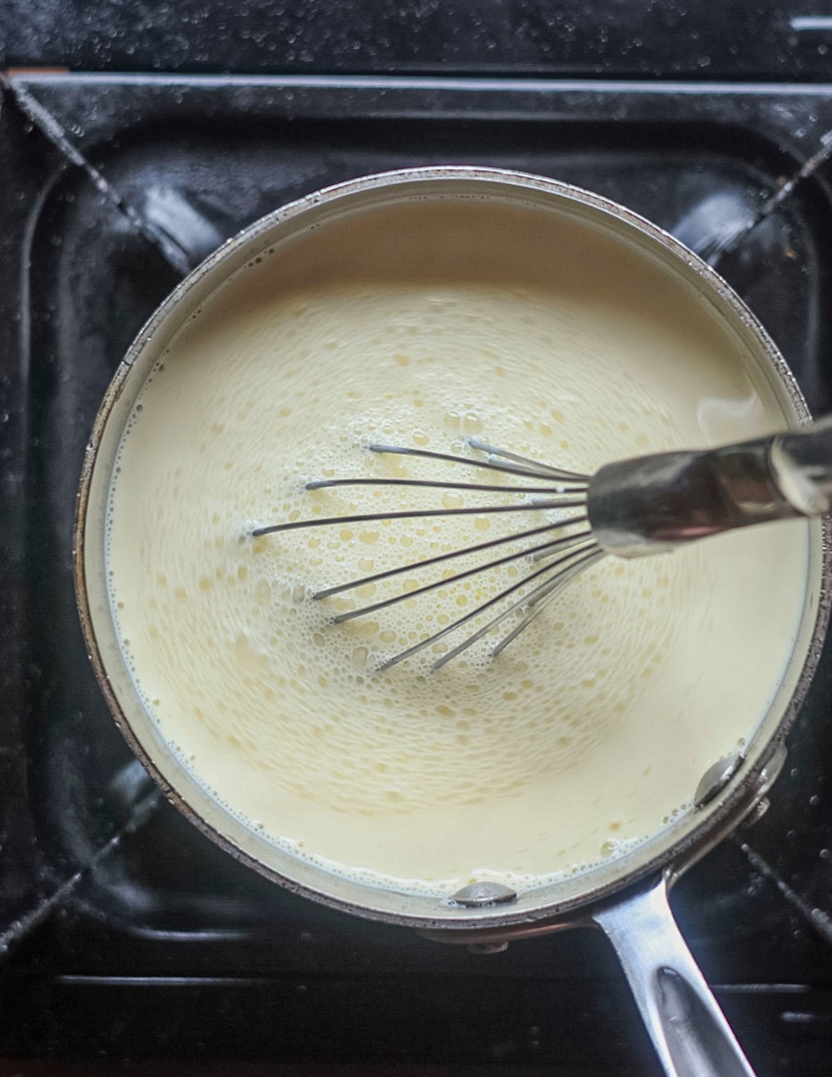 Whisking an ice cream custard as it cooks with a whisk to break up the egg yolks. 