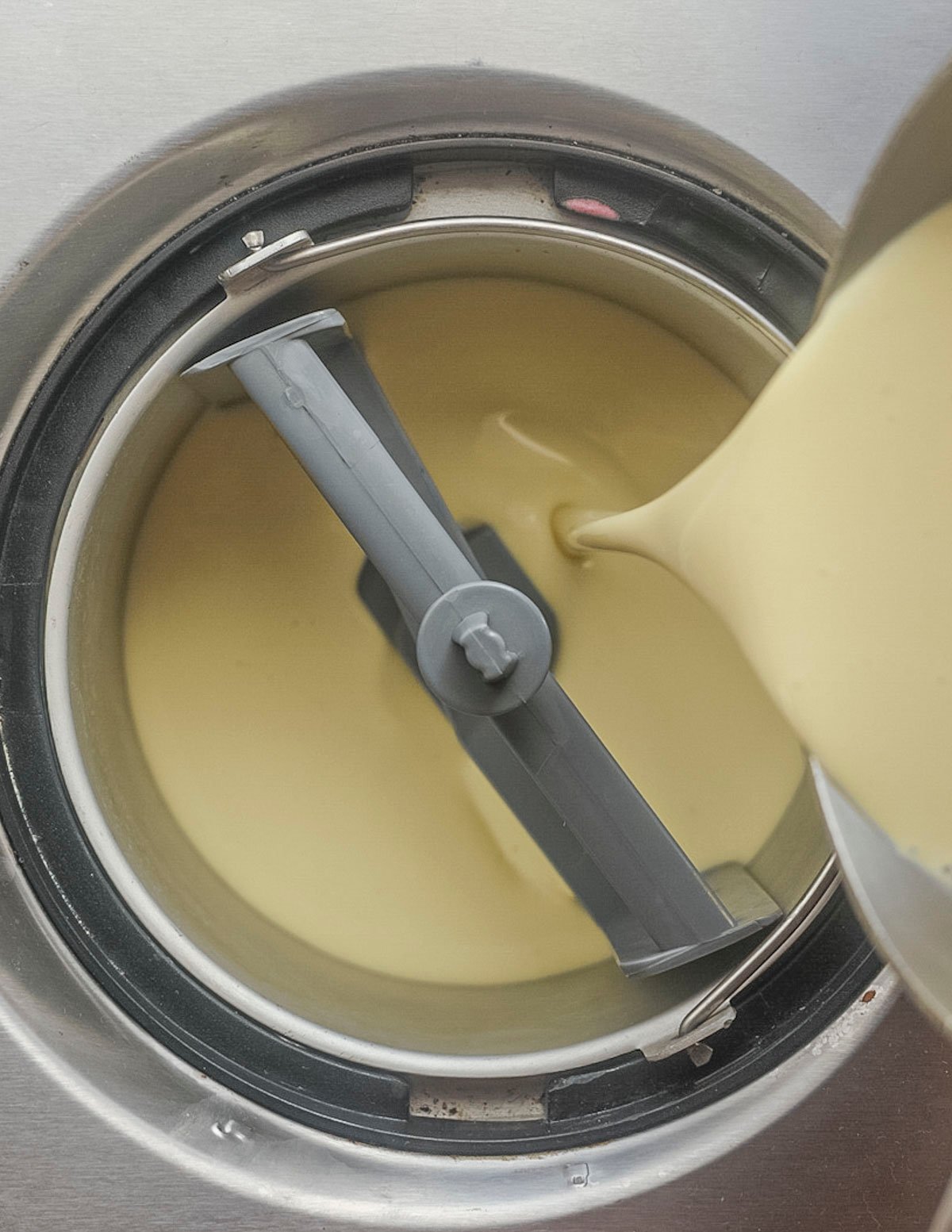 Pouring ice cream custard into an ice cream maker to churn. 