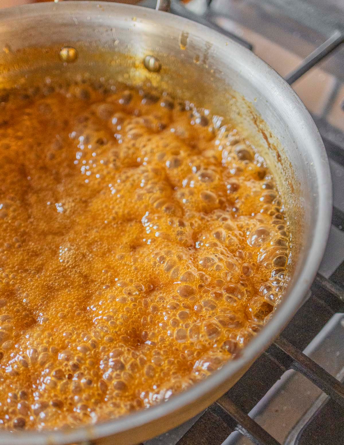 Boiling pear juice caramel in a pan showing large bubbles. 