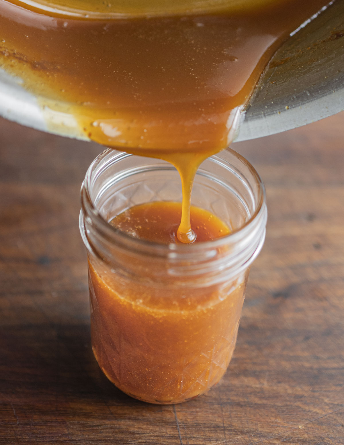 Pouring a finished pear caramel syrup into a jar for storage. 