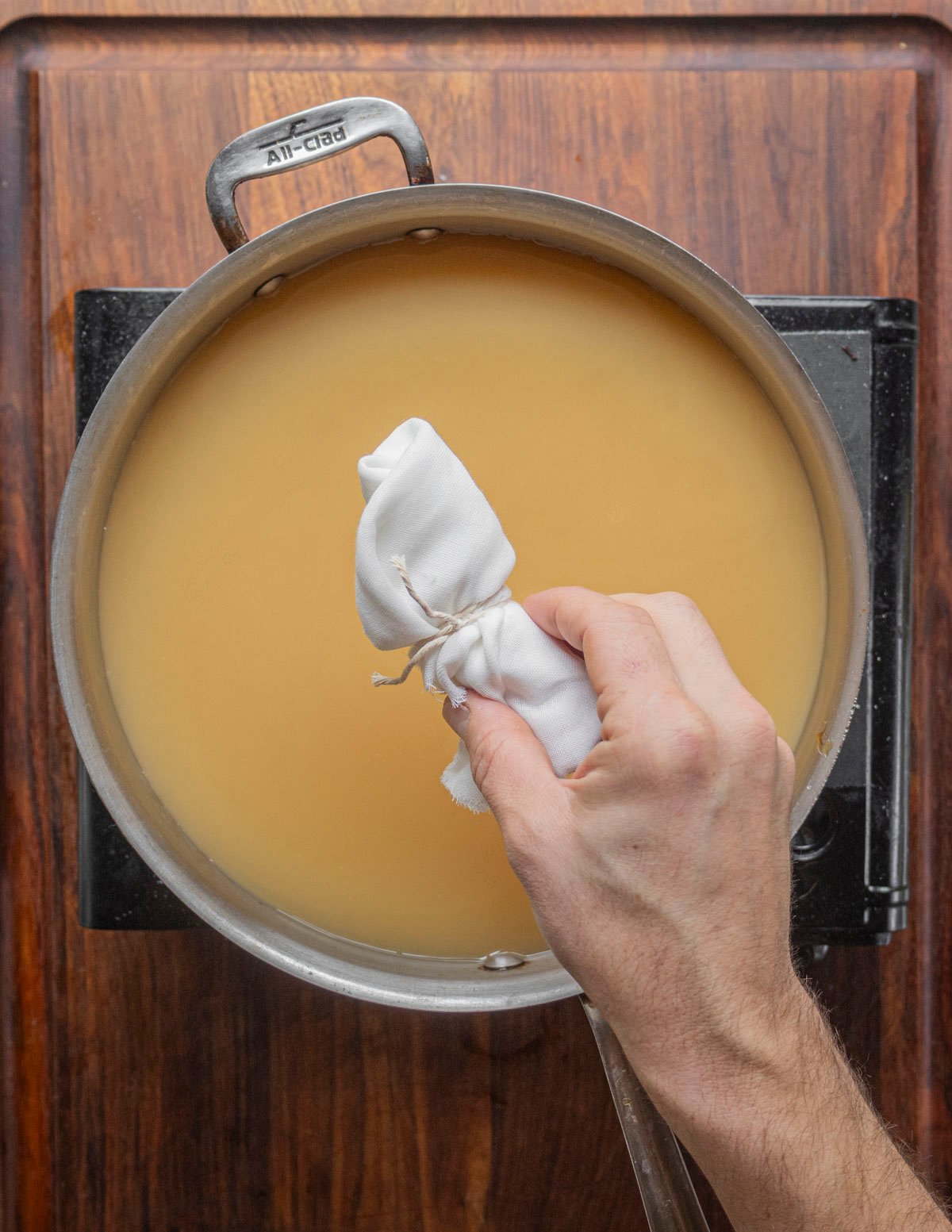 Adding a spice bouquet to a pan of pear juice. 