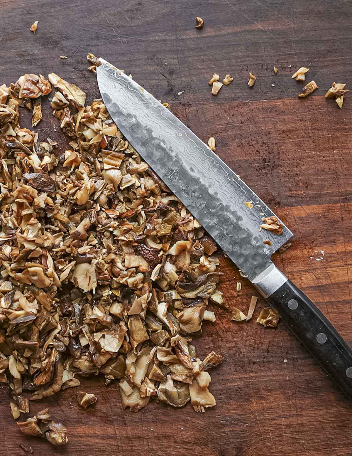 Mincing dried, rehydrated porcini mushrooms with a heavy chefs knife. 