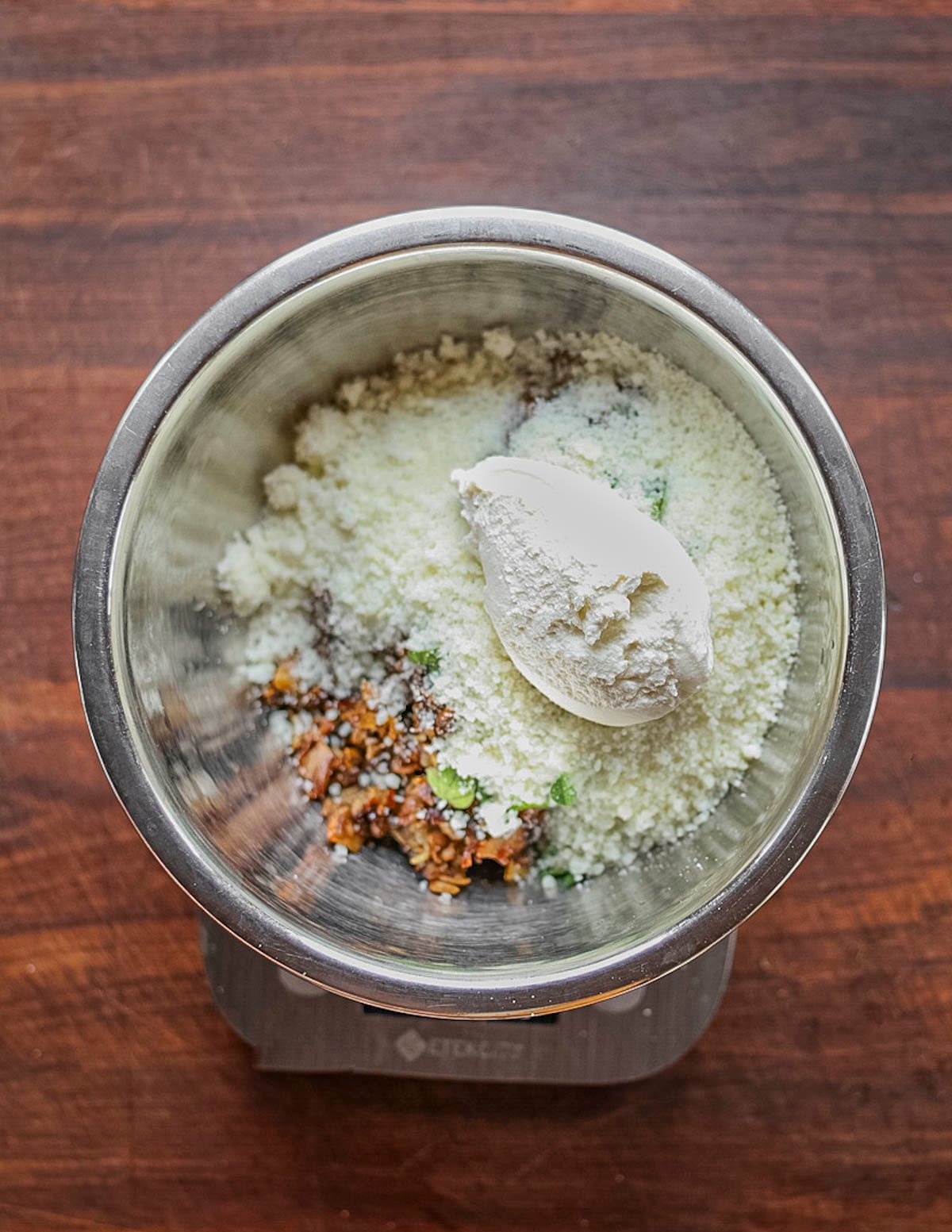 Mixing grated pecorino and ricotta cheese into a bowl of cooked porcini mushrooms. 