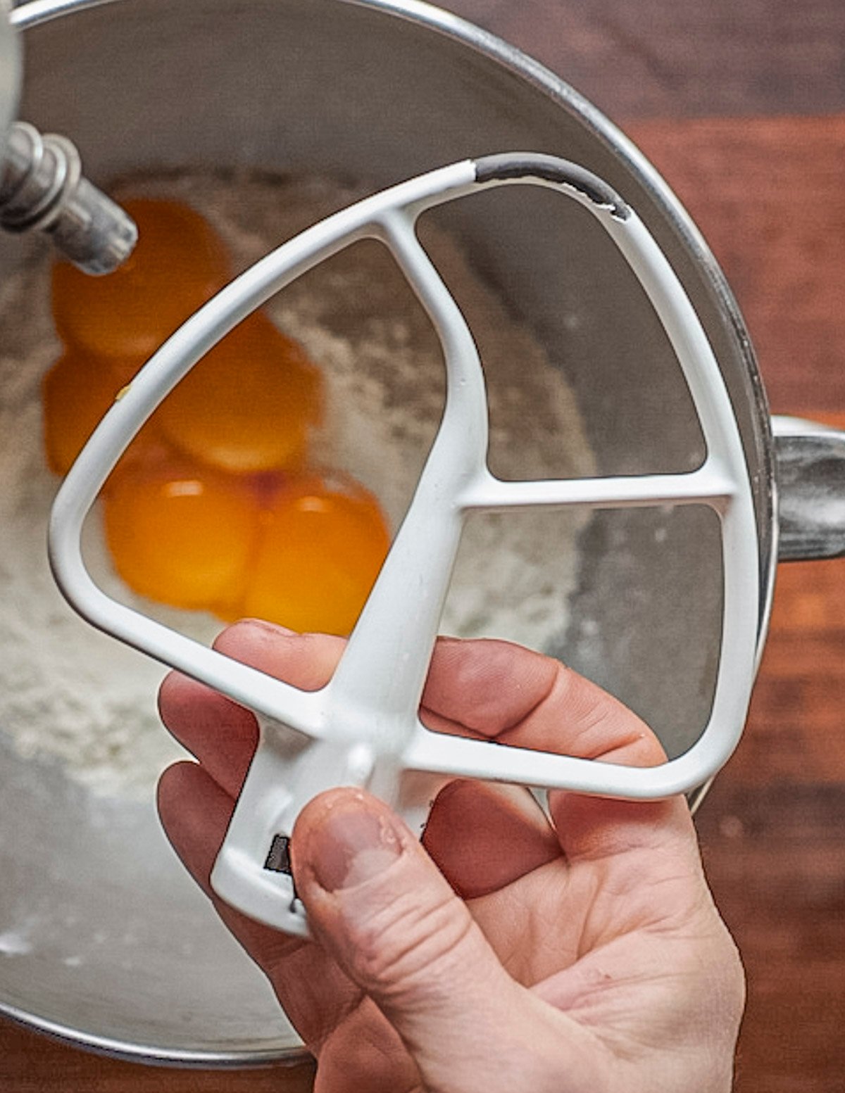 Illustrating mixing egg yolks and flour to make pasta dough using a dough paddle attachment. 