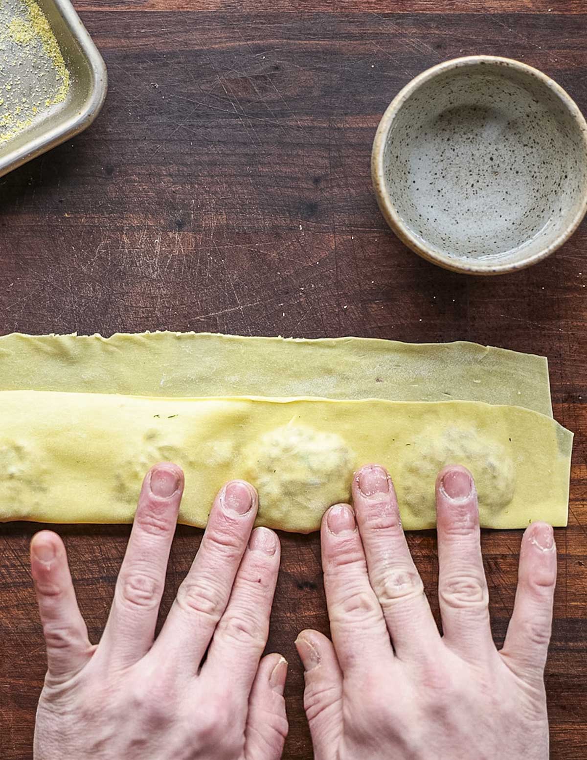 Pressing out air pockets between spoonfuls of ravioli filling. 