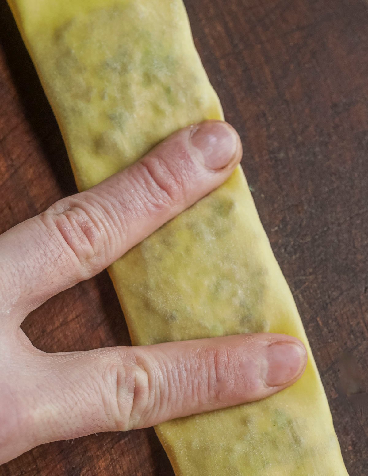 Pressing pasta dough down between mounds of filling to help ravioli stick together. 