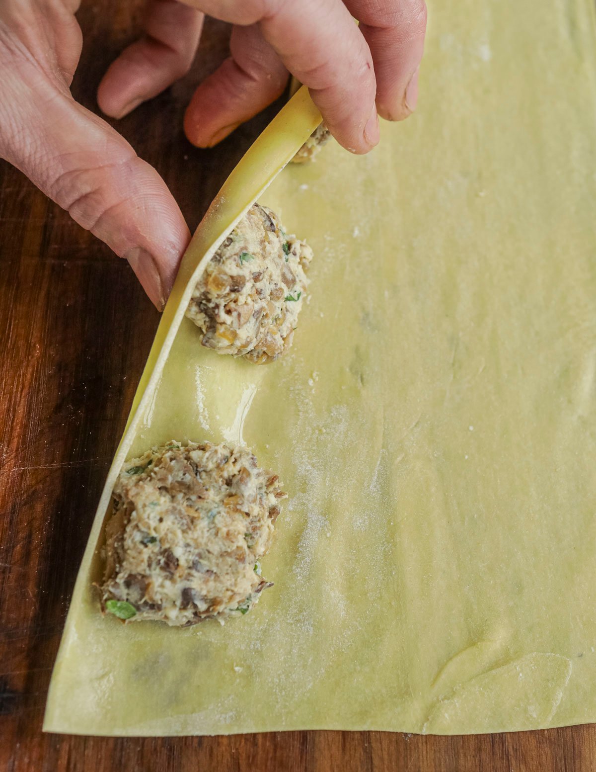 Rolling a sheet of pasta over fillings to make ravioli. 