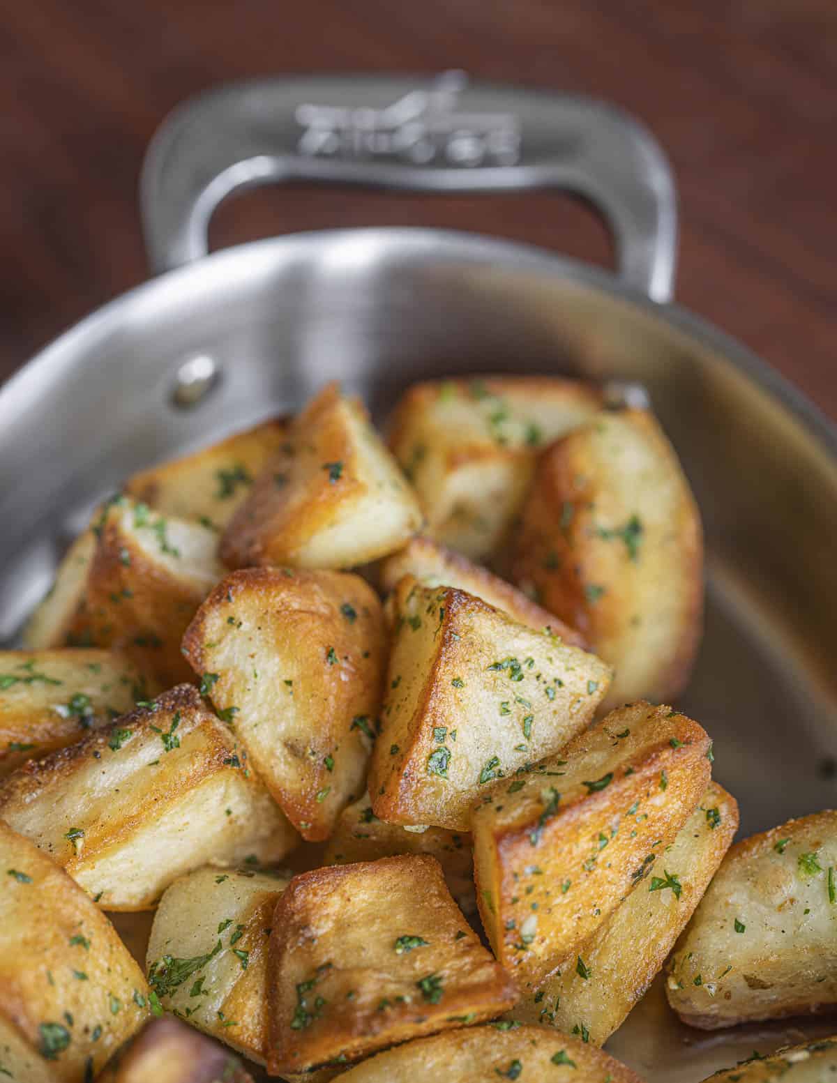 A dish of crispy roasted goose fat potatoes tossed with garlic and parsley.