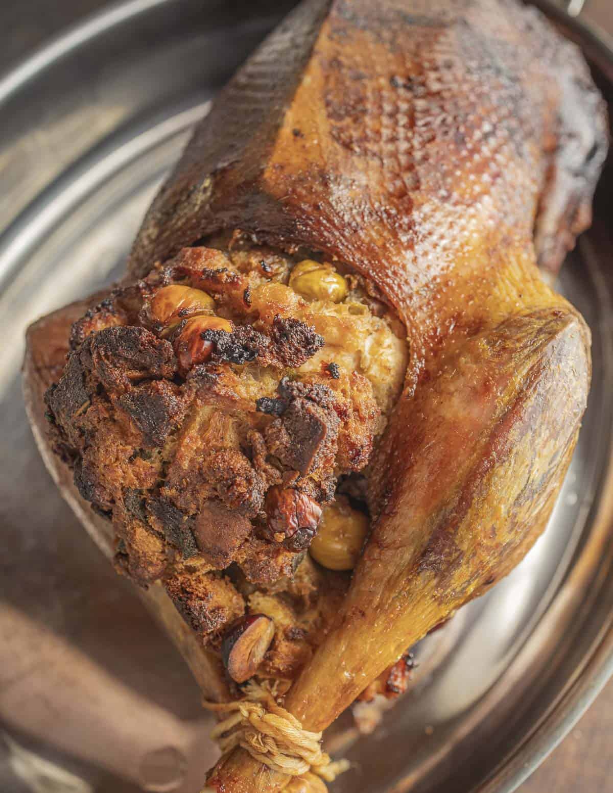 A whole roasted goose cooked golden brown filled with stuffing and ready to carve. 