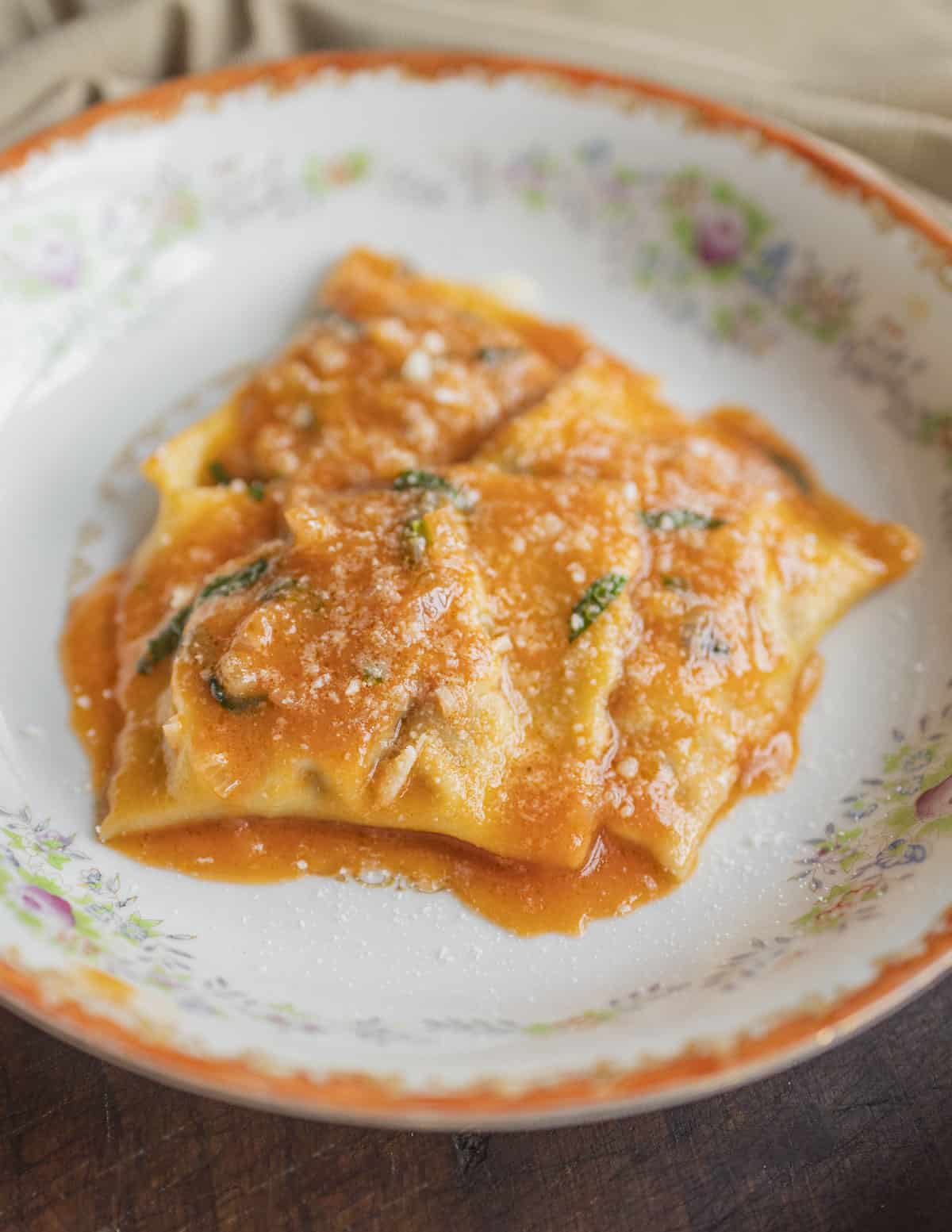 Mushroom ravioli on a plate dressed with tomato beer butter sauce. 