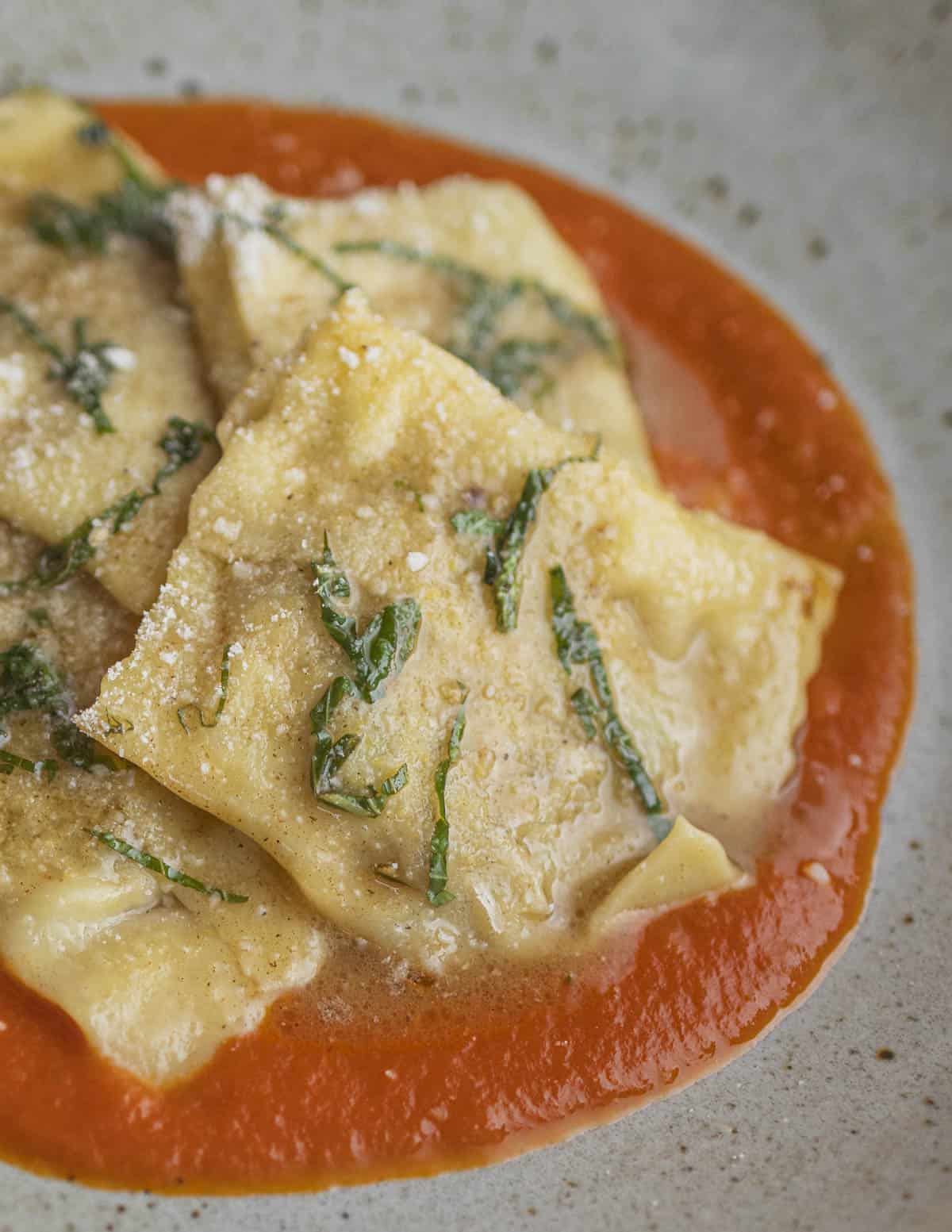 Ravioli in a browned butter sauce on top of tomato marinara. 